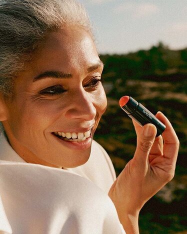 Happy customers in front of a green nature landscape using DOUGLAS make up products