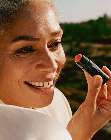 Zufriedene Kundinnen vor einer grünen Landschaft bei der Anwendung von DOUGLAS Kosmetikprodukten